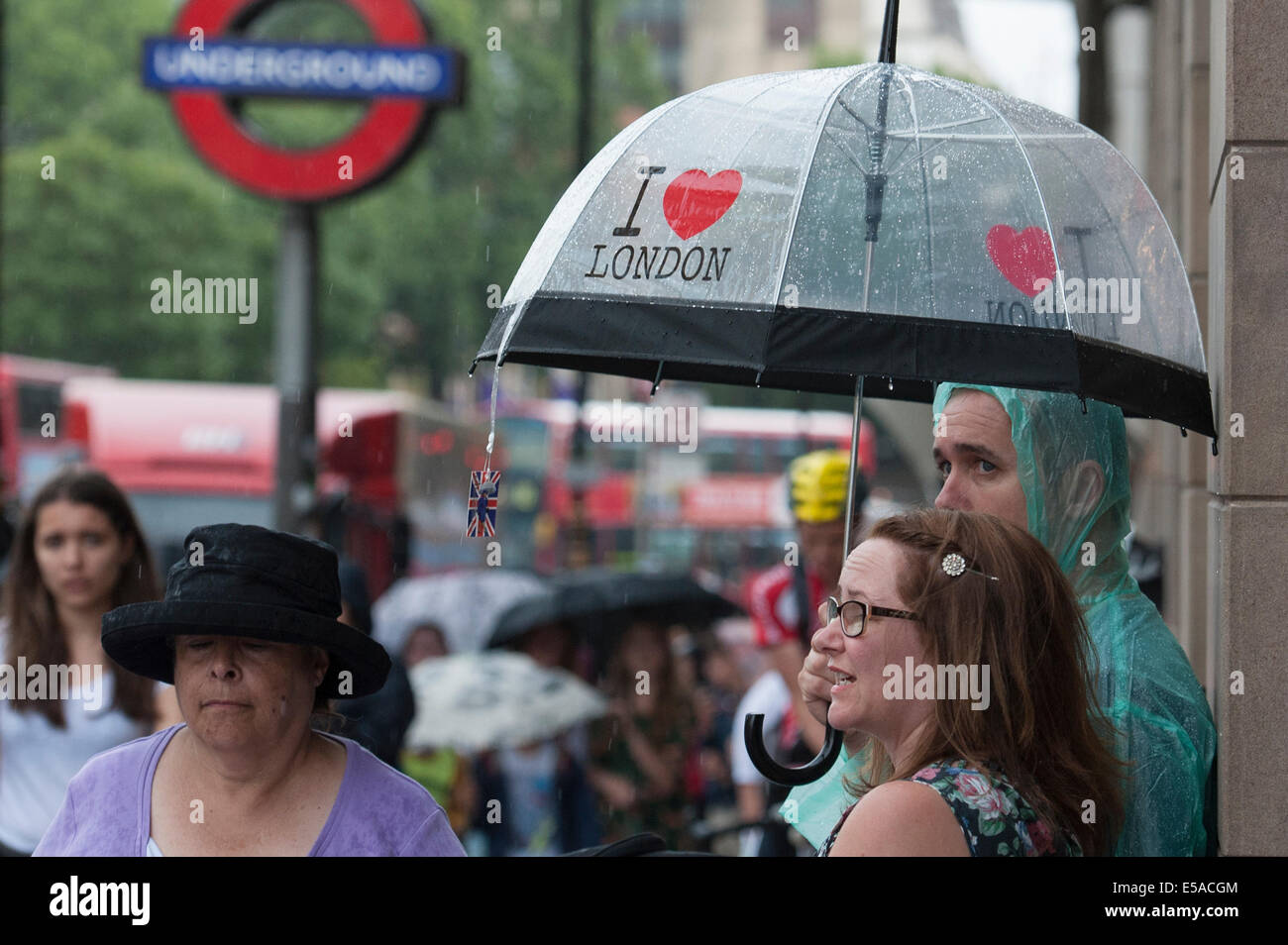 U-Bahn-Station Westminster, London. 25. Juli 2014. UK-Wetter.  Touristen nehmen Sie die Abdeckung am Eingang zur Westminster-u-Bahnstation, wie ein Sturm kurze Erholung von der Hitze des Sommers gab. Bildnachweis: Lee Thomas/Alamy Live-Nachrichten Stockfoto