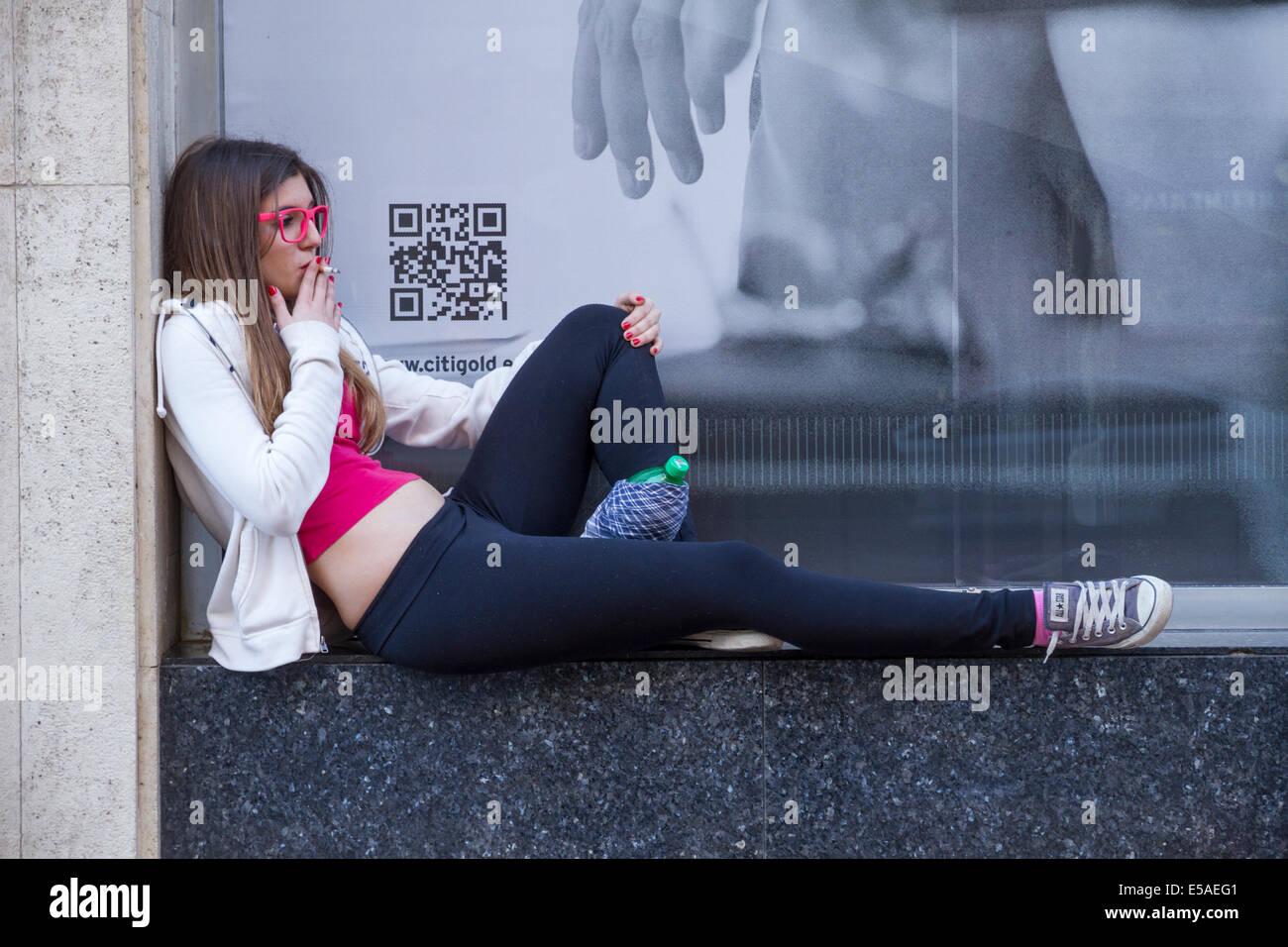 Junges Mädchen am Fensterbrett, während Rauchen in Valencia, Spanien Stockfoto