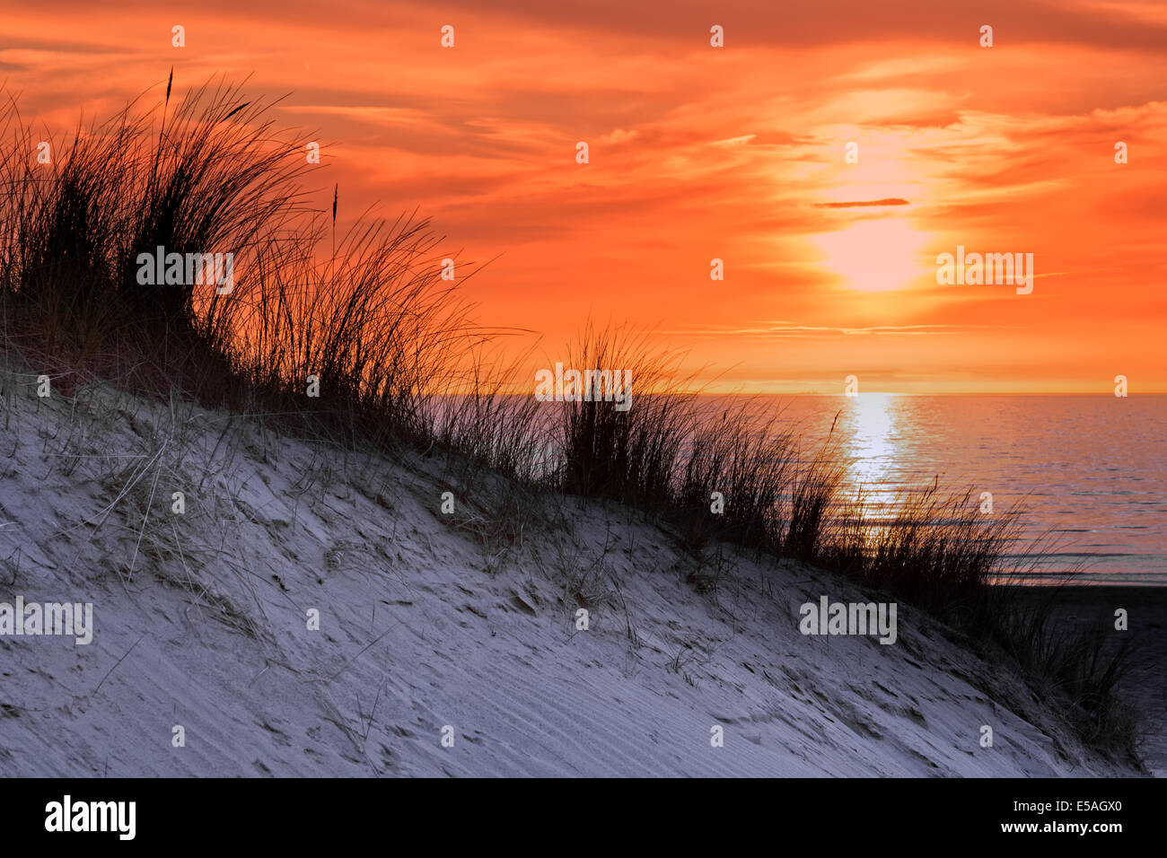 Orange Sonnenuntergang mit Dünen und Meer Stockfoto