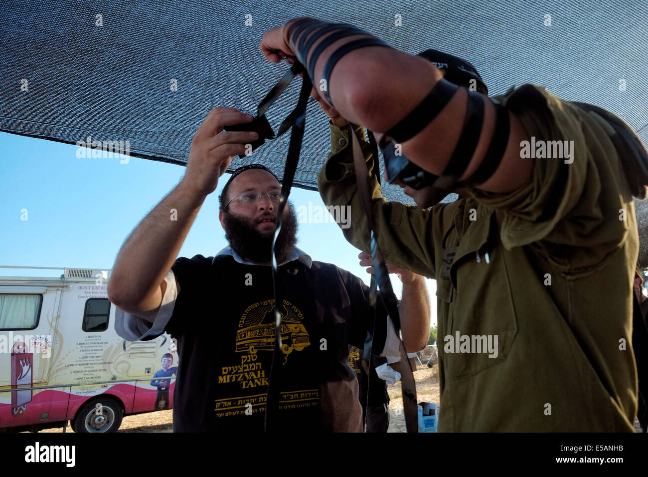Ein Mitglied der religiösen Bewegung Chabads hilft einem israelischen Soldaten, ein traditionelles jüdisches Tfilin zu tragen, wenn er in einem "Mitzva-Panzer" ankommt, das von den orthodoxen jüdischen Praktizierenden des Hasidismus in Chabad-Lubavitch als tragbares "Bildungs- und Öffentlichkeitszentrum" und "Minisynagoge" in Israel verwendet wird Stockfoto