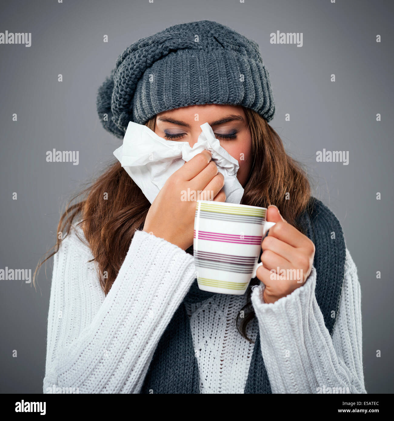 Junge Frau mit Grippe und ihre Nase weht am Taschentuch Debica, Polen Stockfoto