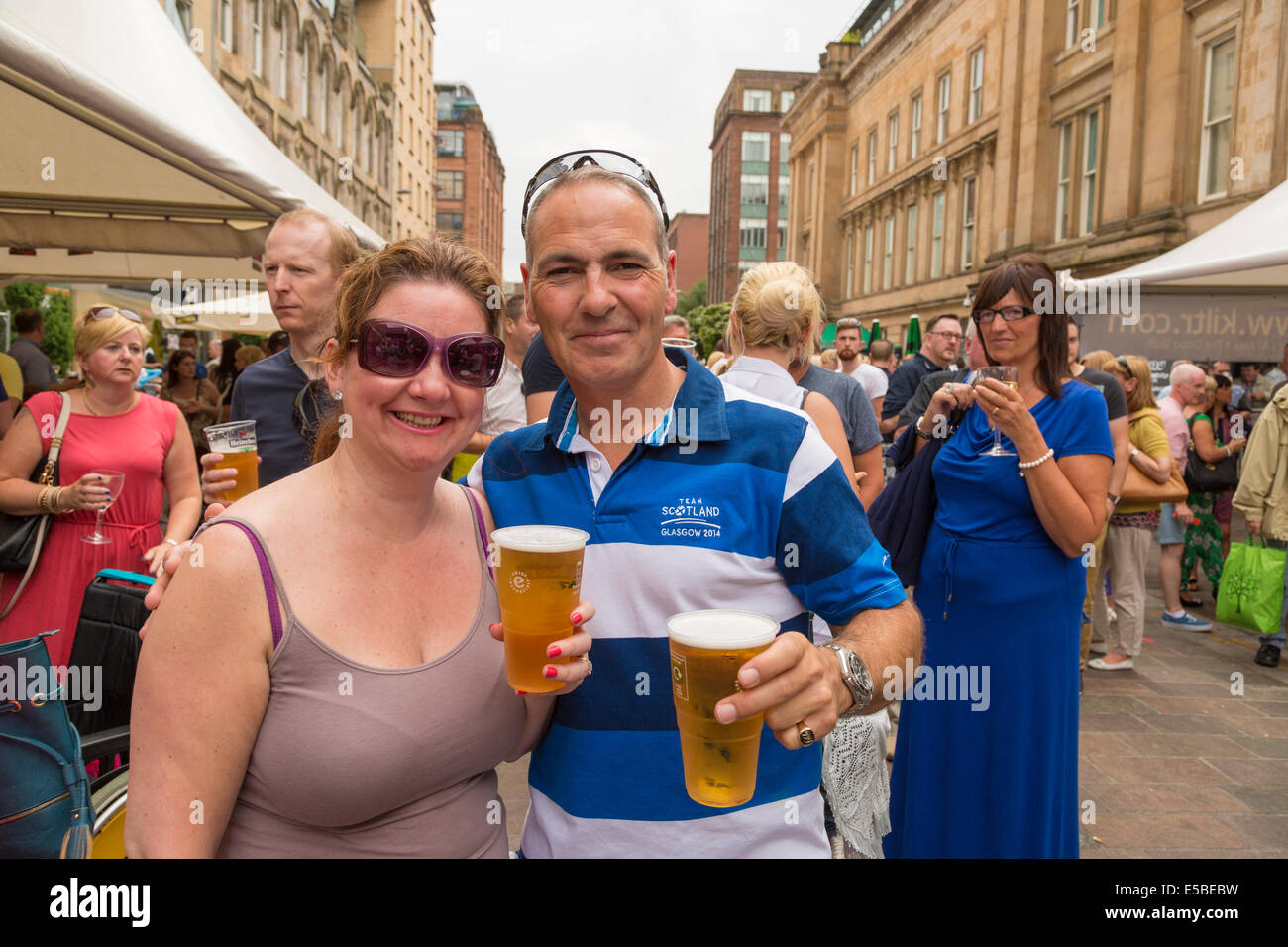 Männliche und weibliche Erwachsene Pints Bier auf der Straße halten und Lächeln. Westend Festival, Glasgow, Schottland, UK, 2014. Stockfoto