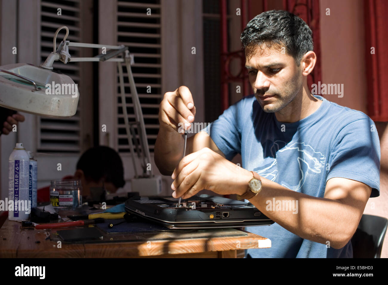Ein junger Mann, der an einem Notebook arbeitet an seiner it-Werkstatt läuft er aus seinem Haus in der Innenstadt von Havanna, Kuba Stockfoto