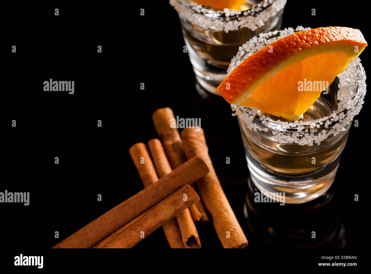 Gold Tequila mit Orange und Zimt auf schwarzem Hintergrund zu reflektieren Stockfoto