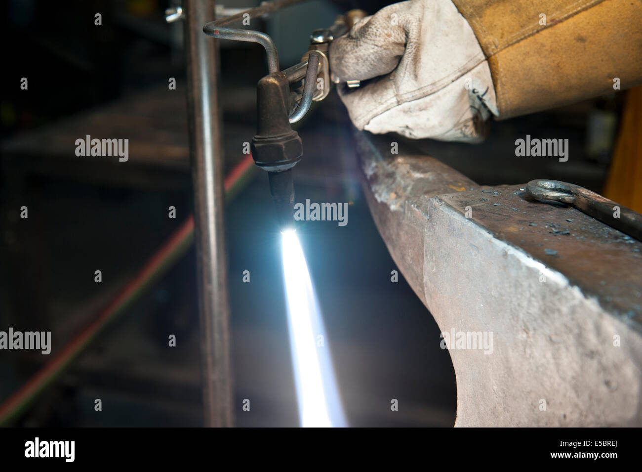 Ein Metallbauer mit Hilfe einer Taschenlampe, um ein Stück Metall zu heizen, um es zu gestalten. Stockfoto