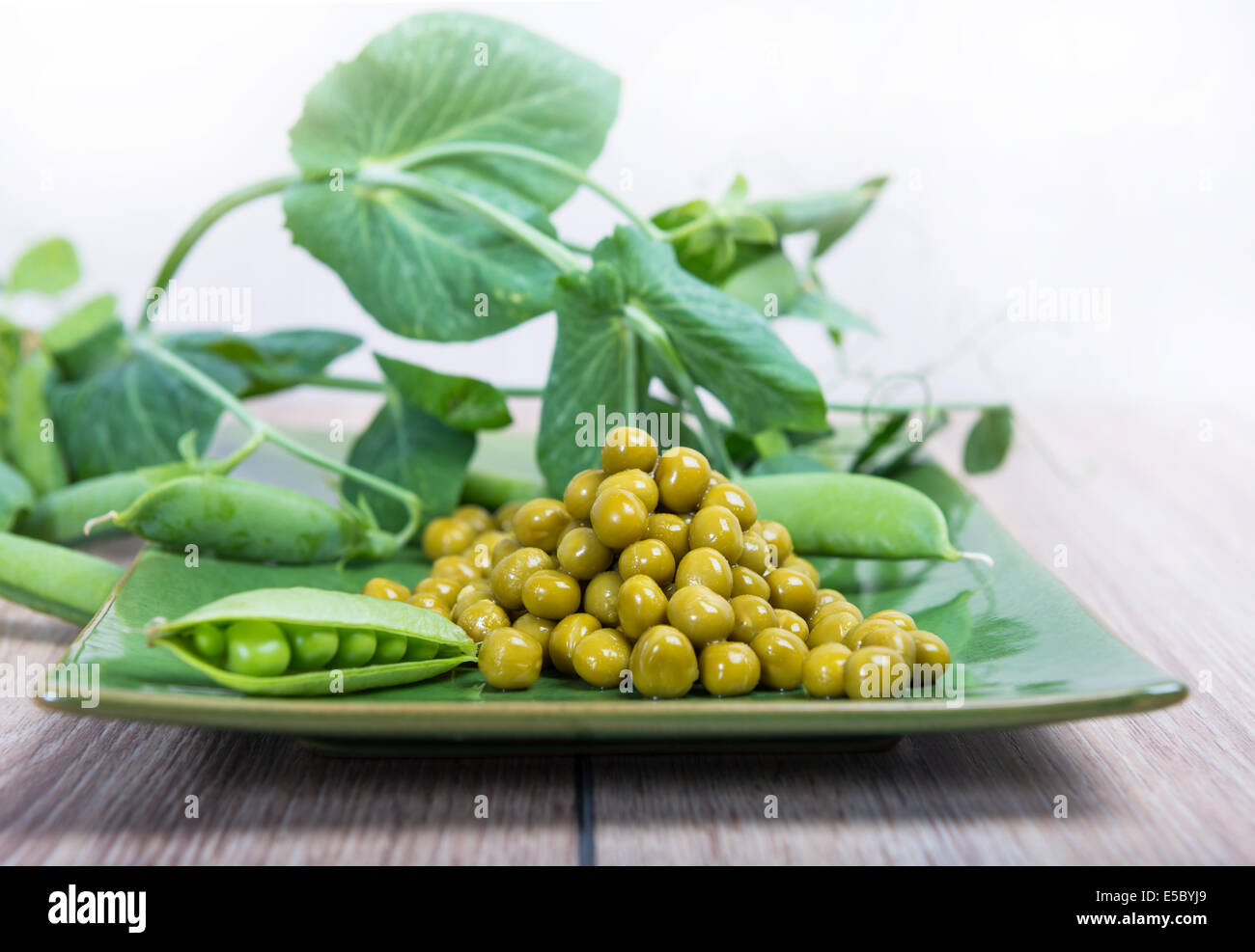 Gekochte grüne Erbsen auf einem Teller, Hülsen und Niederlassungen Stockfoto
