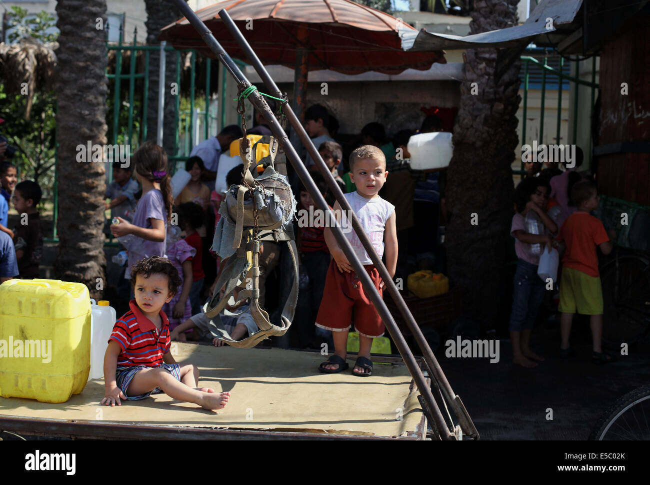 Gaza-Stadt, Gazastreifen, Palästinensische Gebiete. 27. Juli 2014. Palästinenser Kinder füllen Kunststoff-Flaschen und Wasserbehältern mit Trinkwasser aus einem öffentlichen Hahn in Jabalia im nördlichen Gazastreifen am 27. Juli 2014. Beschuss, wie das israelische Militär wieder seinen Angriff auf Gaza, nachdem Hamas eine längere Ruhepause von Israel akzeptiert gemieden wurden drei Palästinenser getötet, Sanitäter sagte Credit: Ashraf Amra/APA Bilder/ZUMA Draht/Alamy Live News Stockfoto