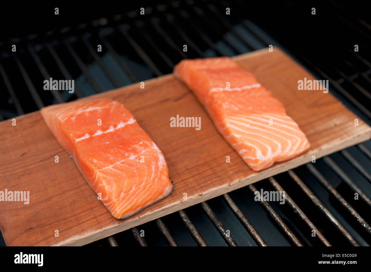 Ein paar rohe wild Alaskan Lachsfilets auf eine Zeder Planke gegrillt. Stockfoto