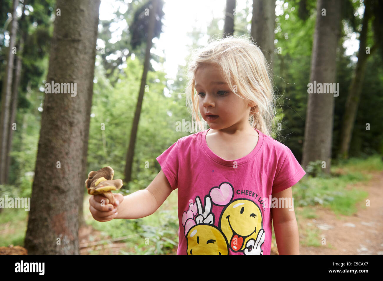 Porträt von glückliches Kind blondes Mädchen, Kommissionierung und Transport volle Händen der Pilze draußen im Wald Stockfoto