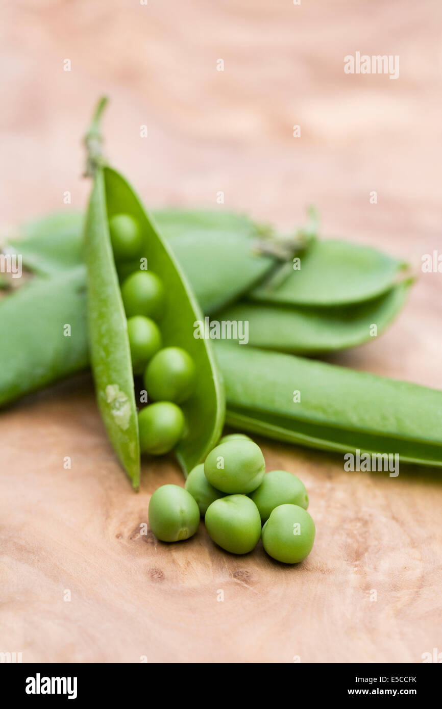 Pisum Sativum. Frisch gepflückt Erbsen auf einem Holzbrett. Stockfoto