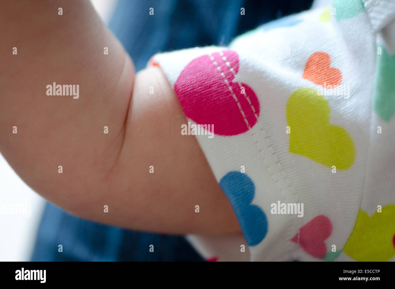 Babymädchen drei Wochen alt und Arm Bizeps posierte in Strampler mit Herz-Motiv Stockfoto
