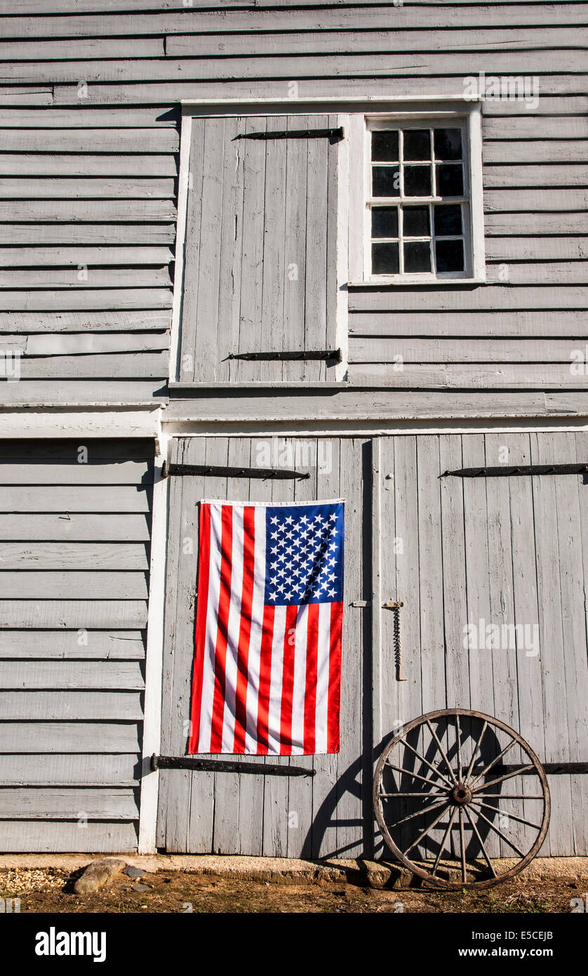 Koloniale amerikanische Flagge an der Scheunentür mit einem antiken Waggonrad, Freehhold Twp., Farm in New Jersey, US-Flagge, Monmouth County Vertical Farming pt Stockfoto