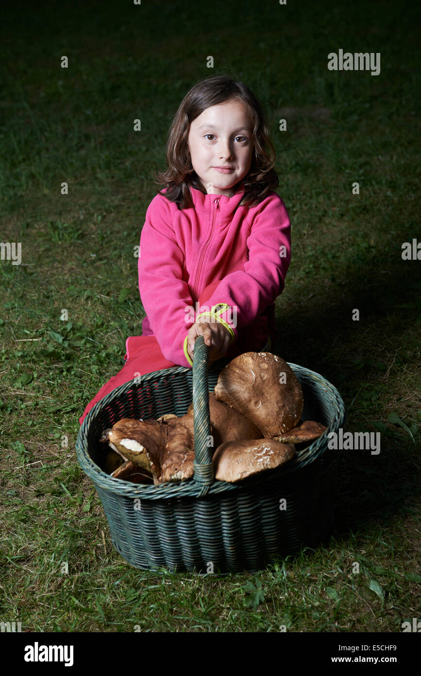 Porträt von glückliches Kind Mädchen tragen volle Korb voller Pilze draußen im Wald Stockfoto