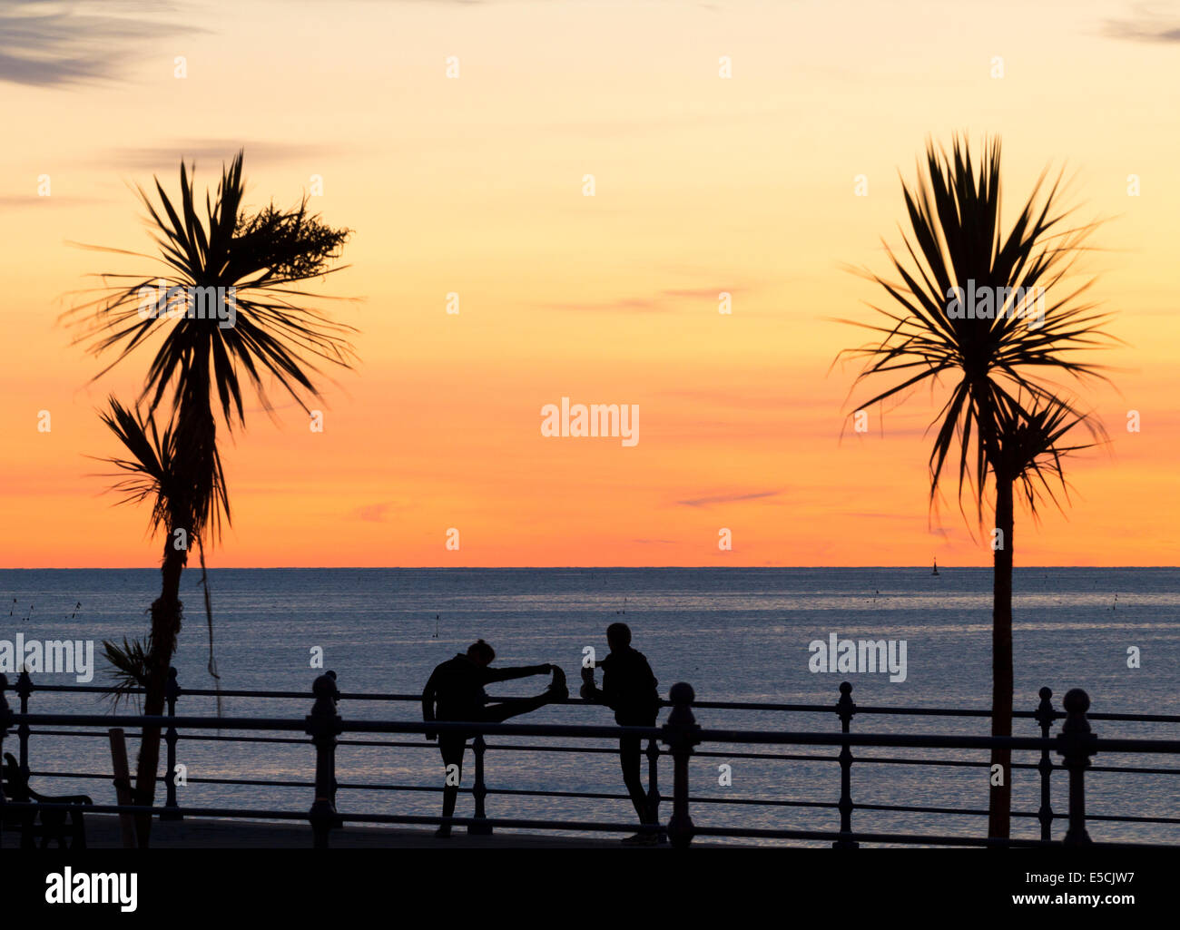 Jogger, Mann und Frau, Aufwärmen, Strecken, Blick auf das Meer, Ozean bei Sonnenaufgang Stockfoto