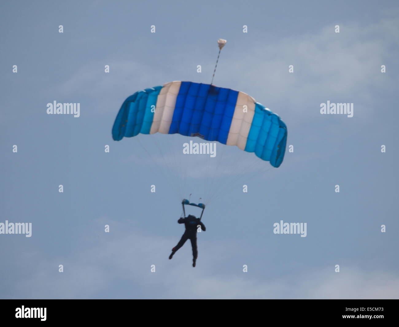 Fallschirm mit blauen Baldachin auf einem blauen Himmel mit ein paar weiße Wolken, pilot erscheint in der silhouette Stockfoto