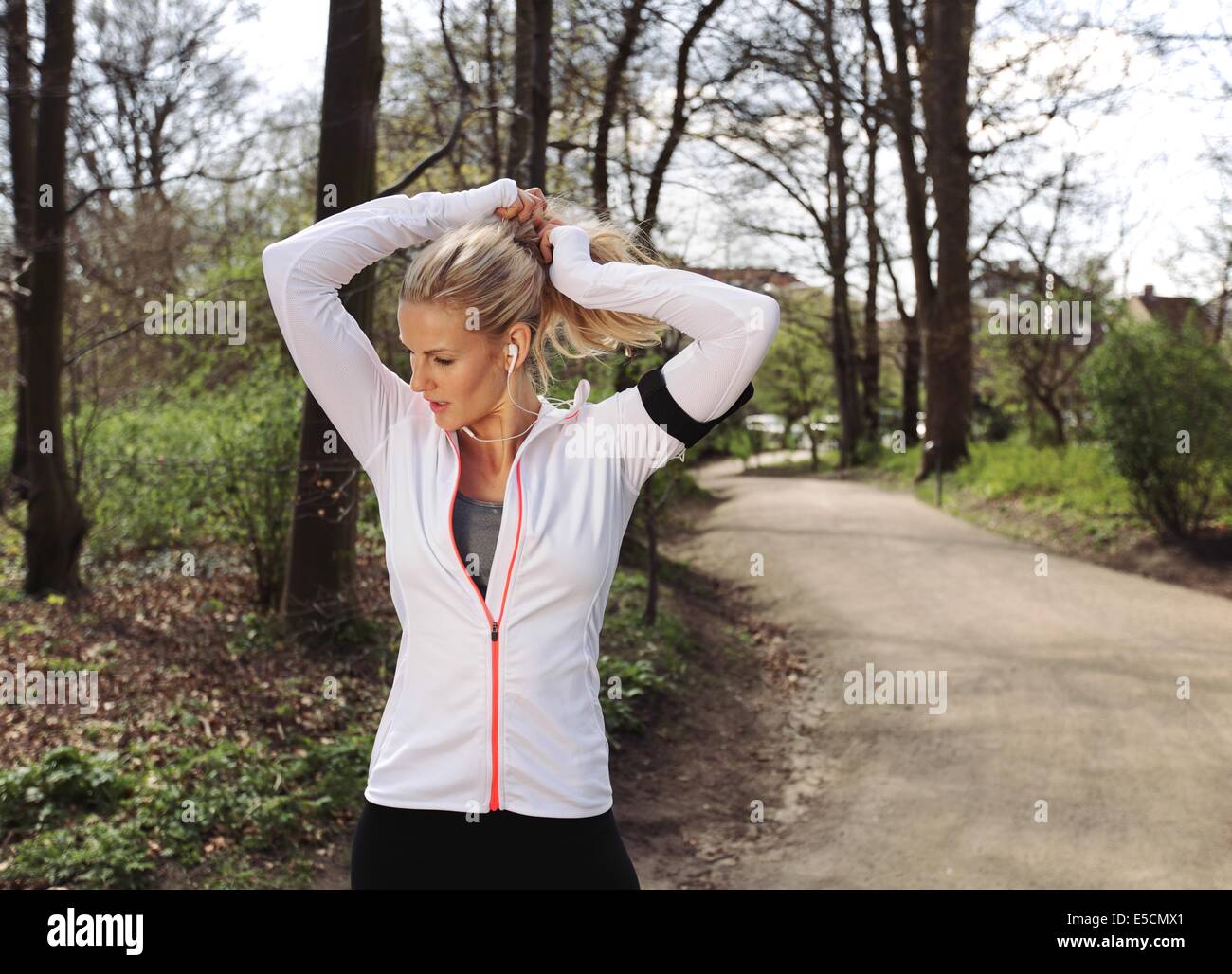 Passen Sie die Sportlerin binden Haare vor ihren Lauf. Hübsche junge Frau ihr Lauf im Wald vorbereiten. Stockfoto