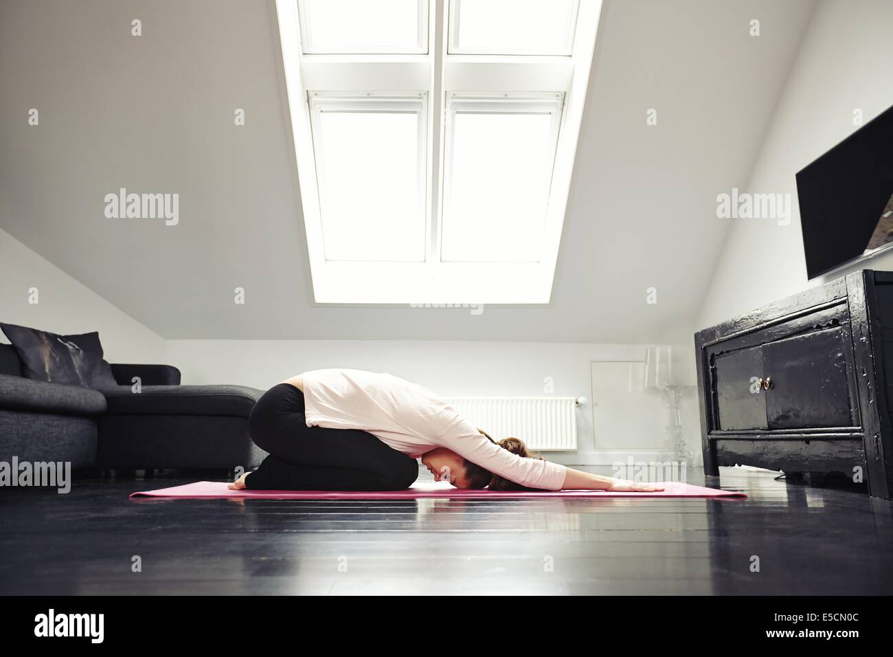 Seitenansicht der kaukasische Mädchen trainieren Yoga in ihrem Wohnzimmer. Weiblich, Entspannungsübung auf Matte zu Hause zu tun. Stockfoto