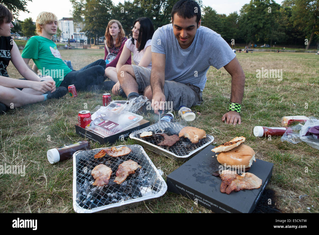 Freunde kochen auf einem Einweg-Grill in einem Park in Brighton Stockfoto