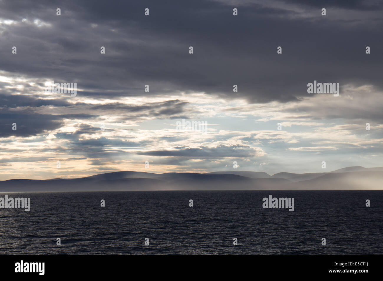Dramatischen Sonnenuntergang über nebligen schottischen Berge aus dem Meer entnommen Stockfoto