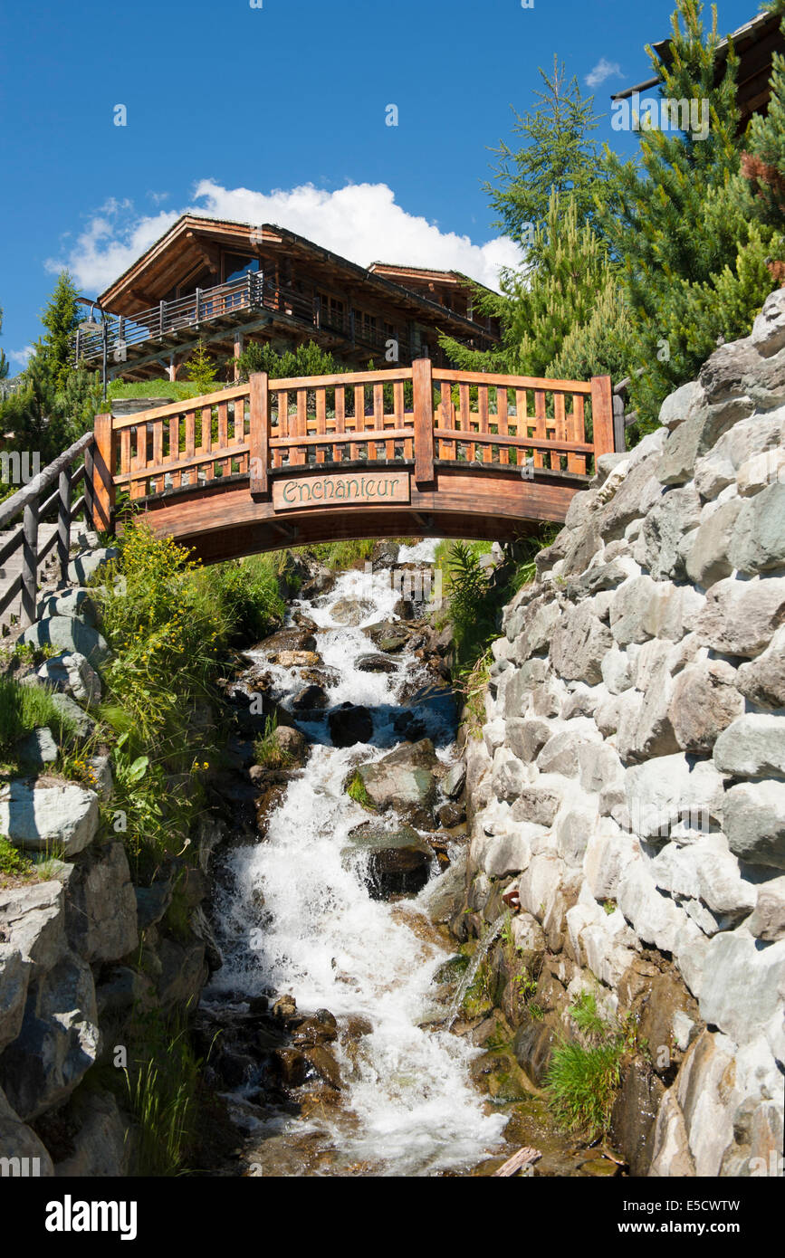 Wohngebiet mit Ferienhäusern und Brücke & Mountain Creek am noblen Urlaubsort von Verbier, Wallis, Schweiz Stockfoto