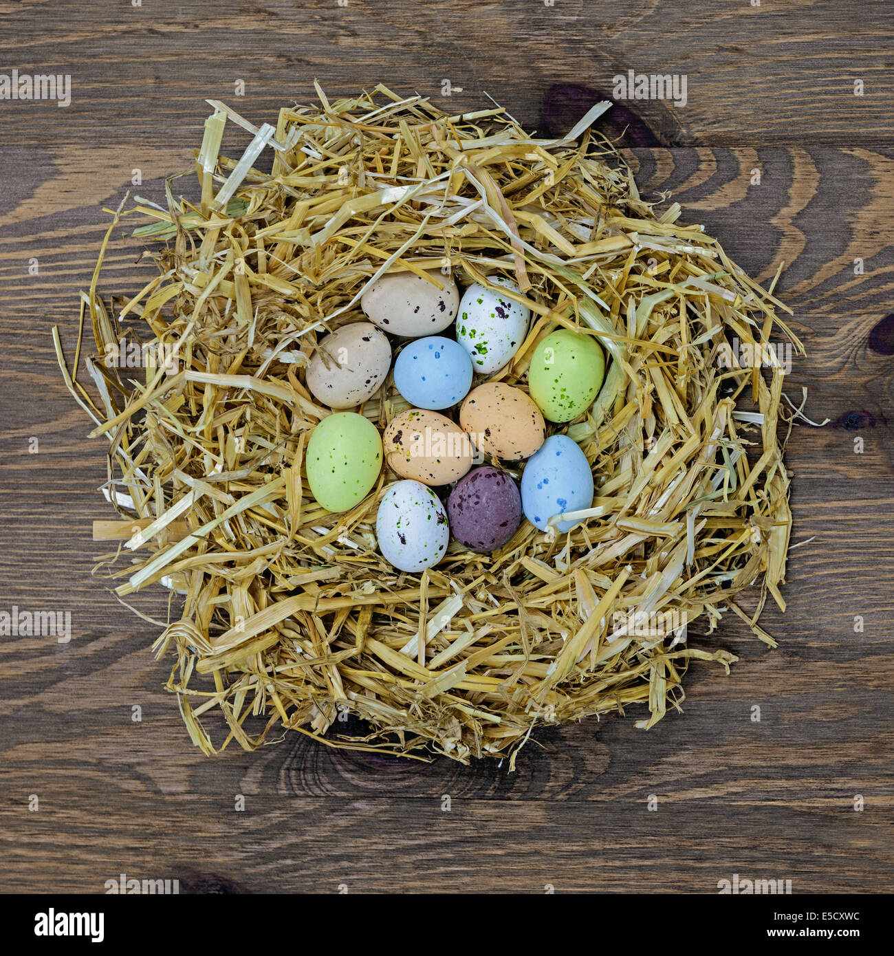 Stroh Nest voller Süßigkeiten bedeckt Ostereier Stockfoto