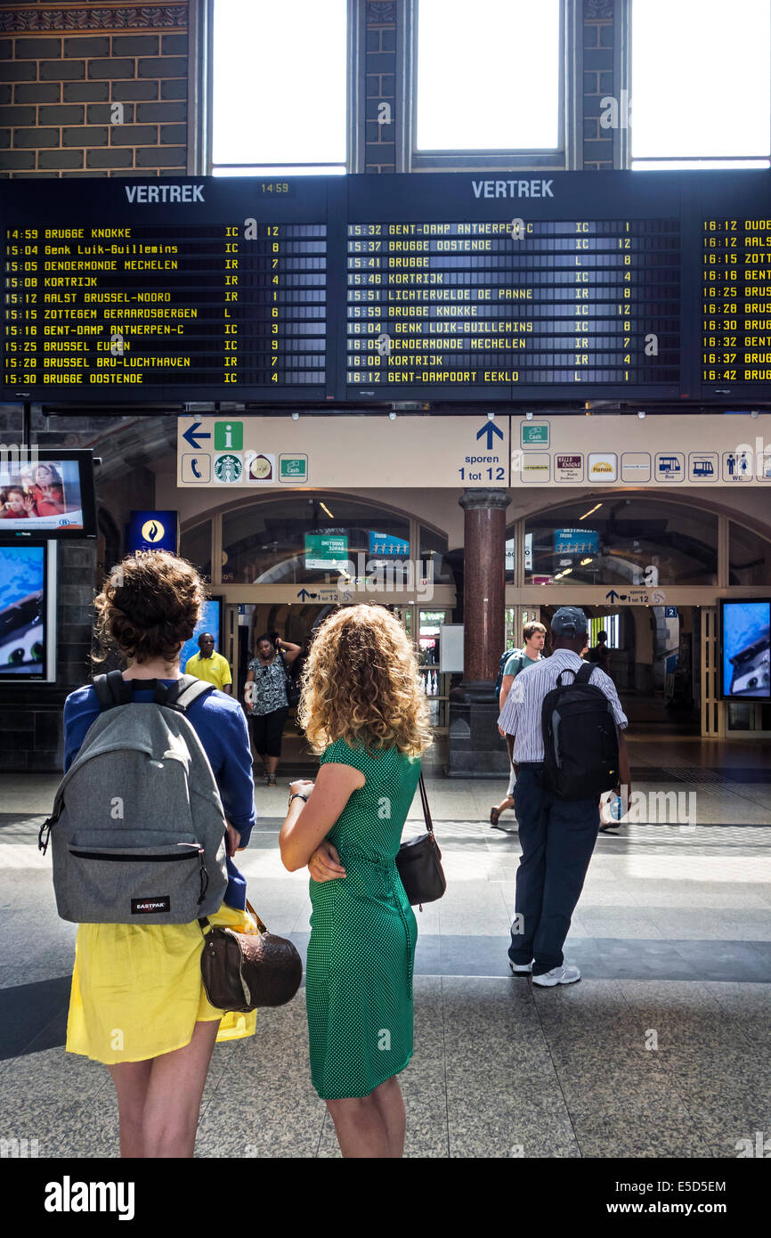 Reisende, die im Fahrplan in der Abflughalle des Gent-Sint-Pieters / Sankt Peter Bahnhof in Gent, Belgien Stockfoto