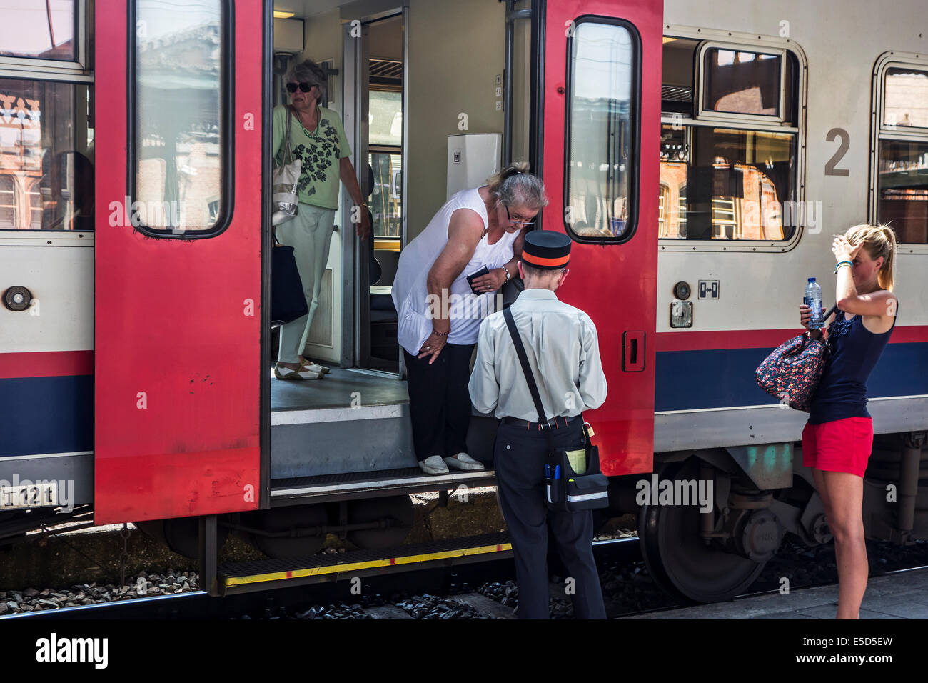 Ältere Fragen an Bahnbeamten Beifahrerin / ticket-Inspektor aus dem Zug am Bahnhof-Plattform Stockfoto