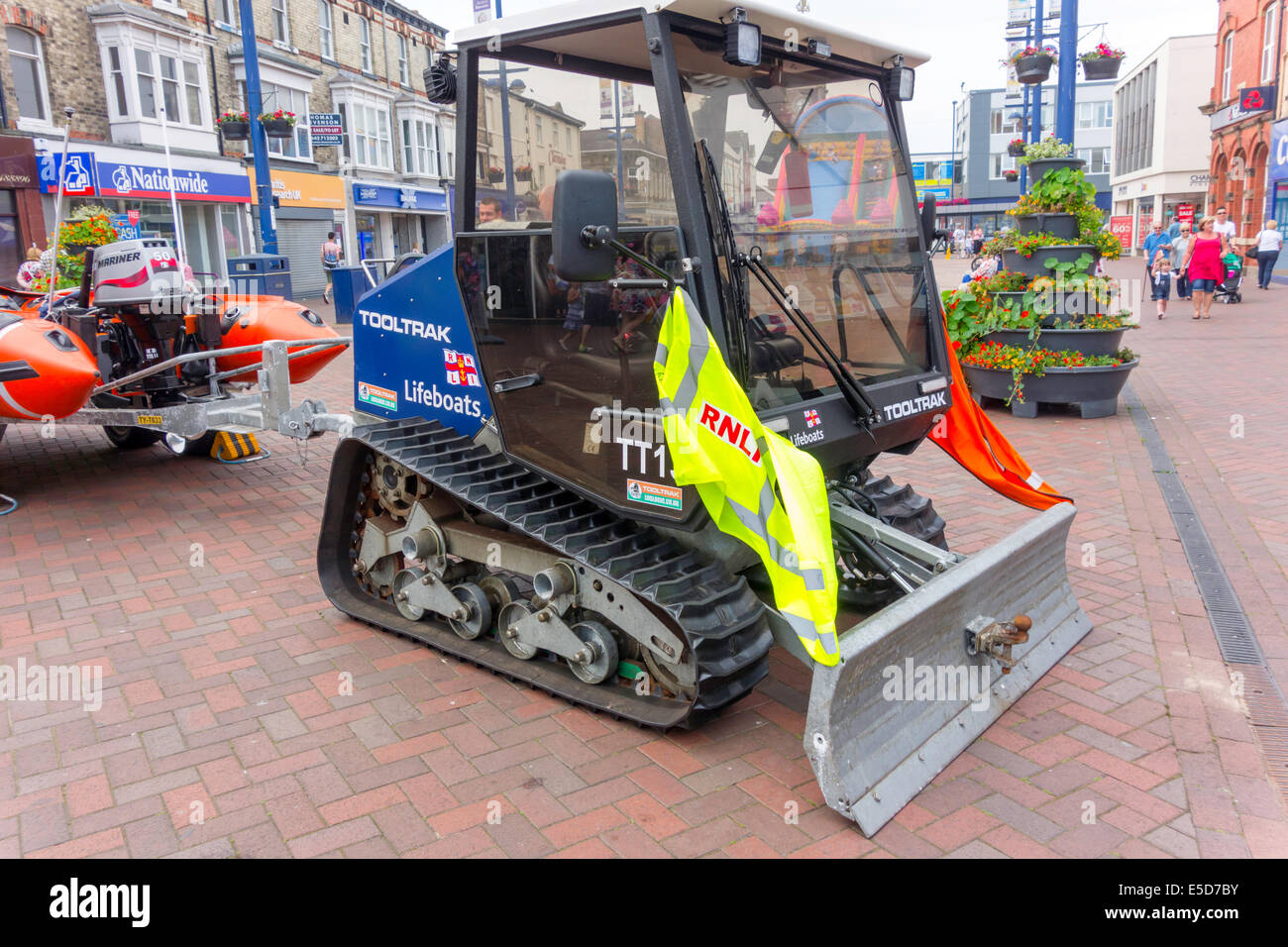 Eine kleine RNLI aufblasbares Rettungsboot mit einem Tooltrak verfolgten Start Traktor auf dem Display in Redcar High Street für Spendenaktionen Stockfoto