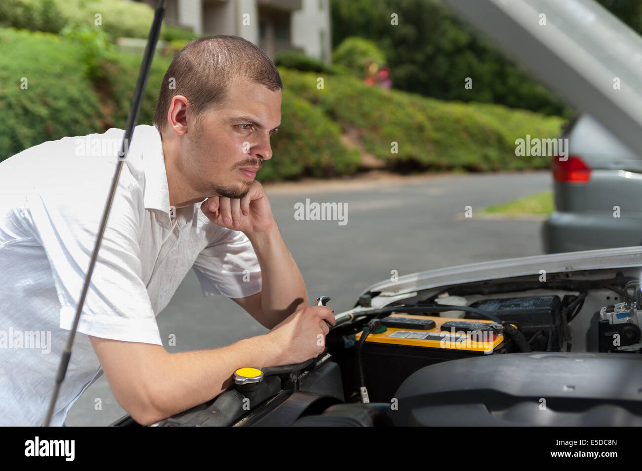 Junger europäische Mann denkt darüber nach, was falsch mit seinem Auto ist Stockfoto