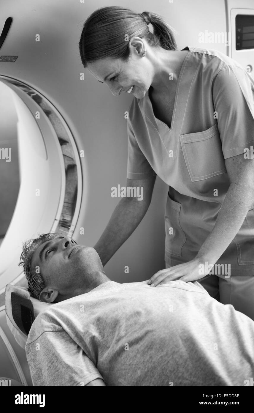 Junger weiblicher Arzt beruhigend Mann MRT-Untersuchung unterziehen. Stockfoto