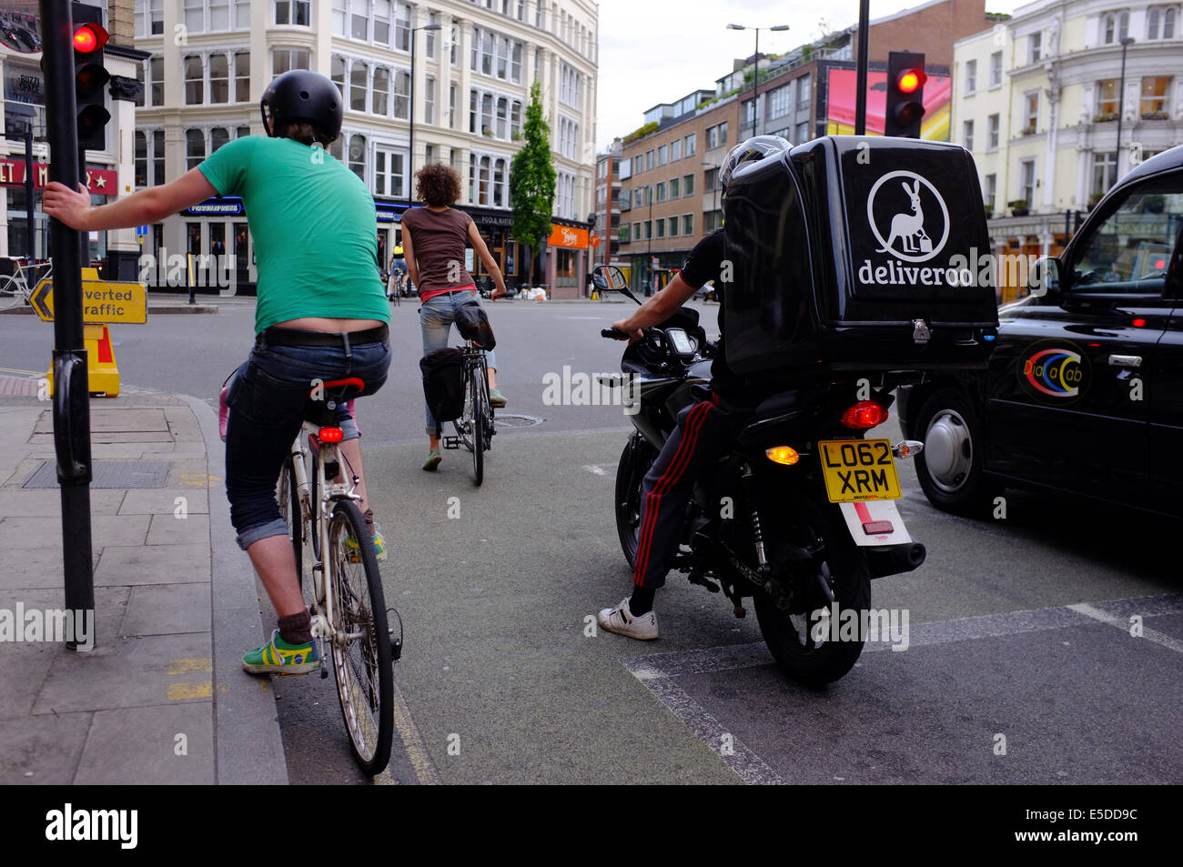 Radfahrer, Motorrad-Kurier & Taxi warten an der Ampel in London Stockfoto