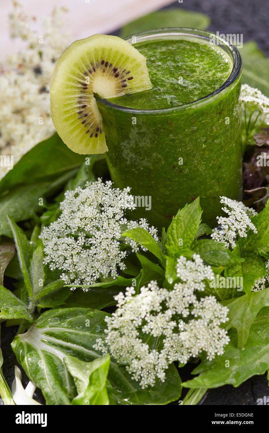Glas grüner Smoothie mit Kiwi-Scheibe, Blätter und Blüten verziert Stockfoto