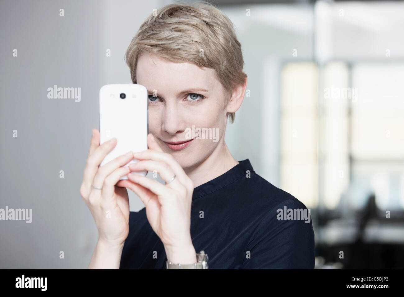 Deutschland, München, Geschäftsfrau im Büro, mit Smartphone Stockfoto