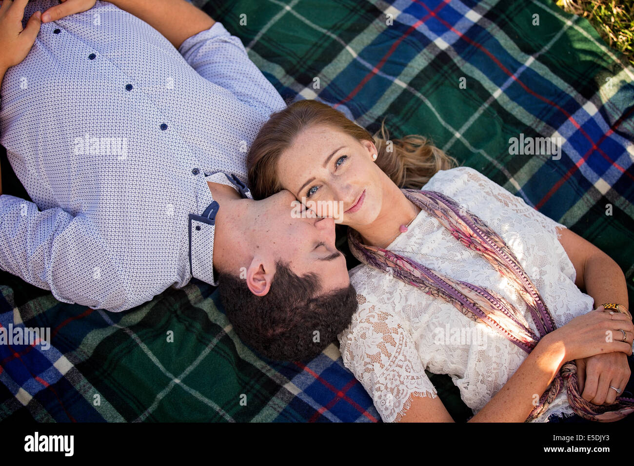 ein junges Paar auf einem Teppich liegend mit männlich Wange küssen Stockfoto