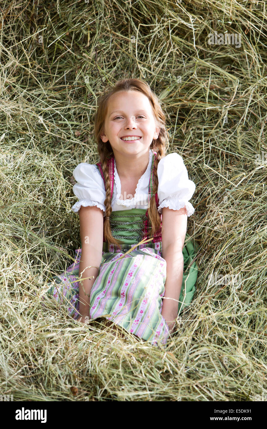 Deutschland, Bayern, Mädchen im traditionellen Dirndl sitzen im Heu Stockfoto
