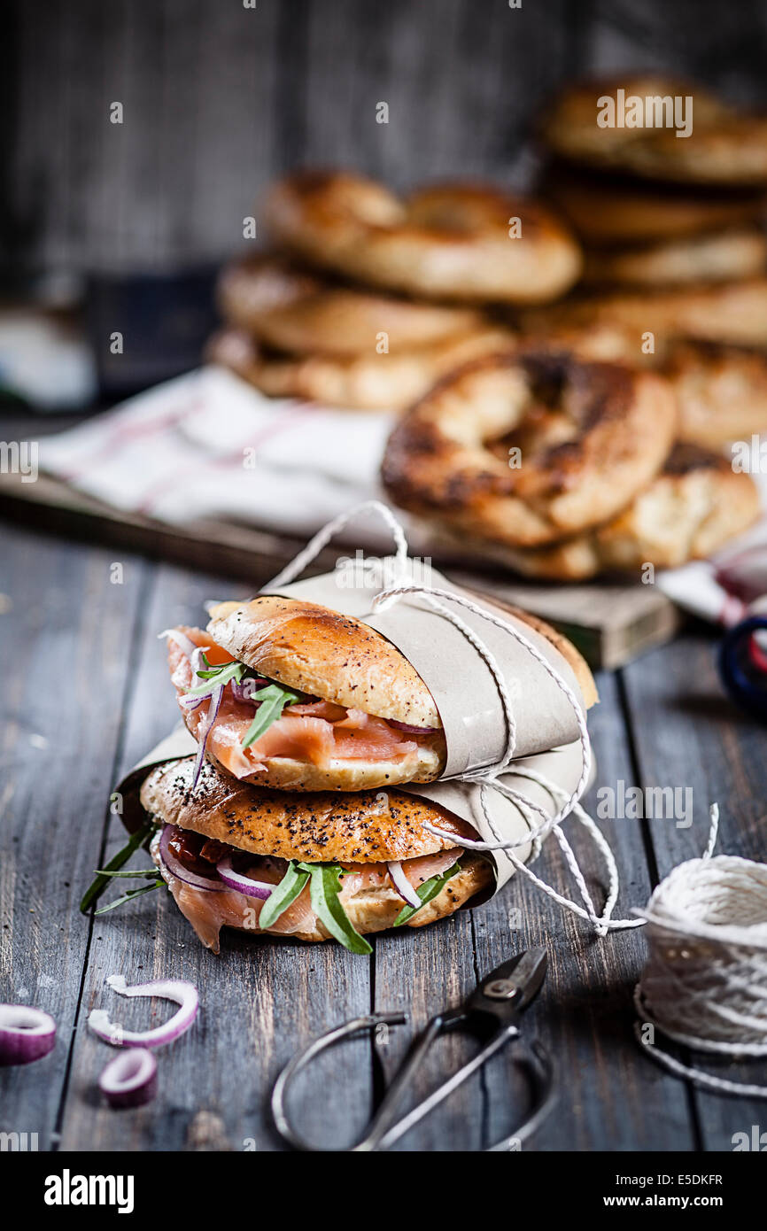 Zwei hausgemachte Bagels eingewickelt in Papier, Schnur und Schere auf Holz garniert Stockfoto