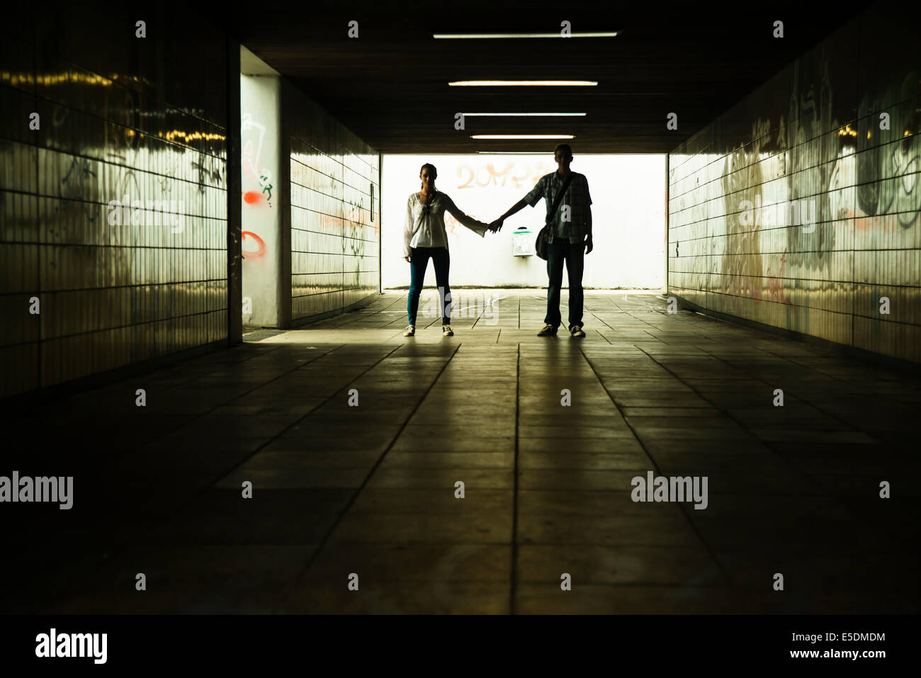 Junges Paar stehen Hand in Hand in eine dunkle Unterführung Stockfoto