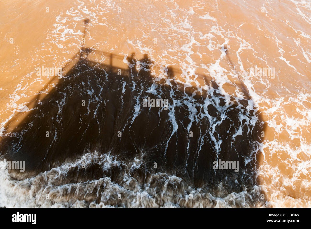 Auf der Suche nach unten auf die Schatten, die von zwei Personen am Ende des Skegness Pier auf der trüben braunen Meer Stockfoto
