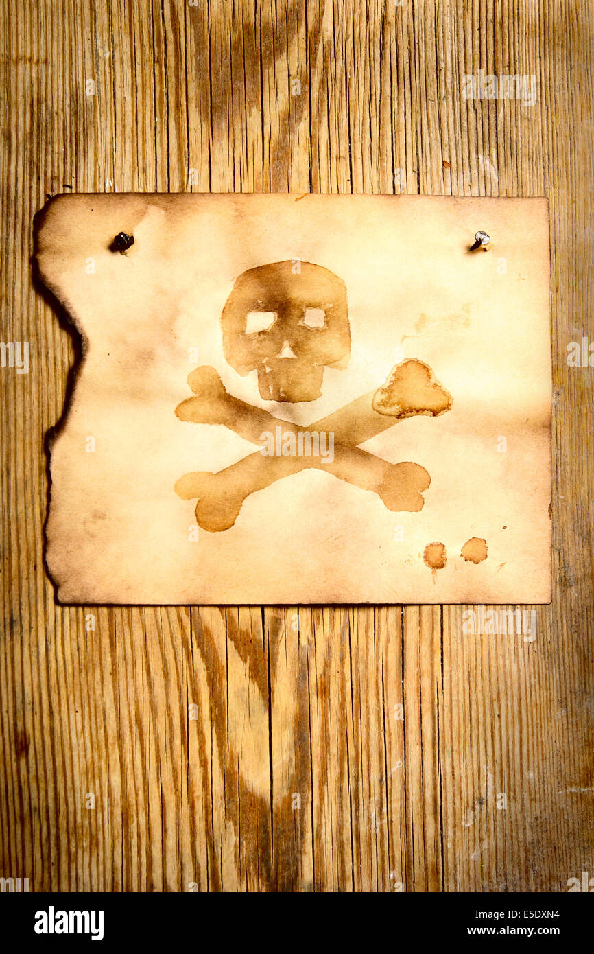 Altes Papier mit Totenkopf an Holzwand befestigt Stockfoto
