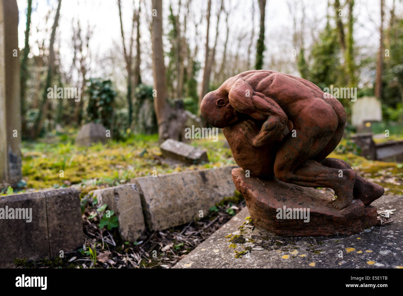 Skulptur eines Mannes schob ein Felsbrocken bergauf wie Sisyphos auf dem Highgate Cemetery. Stockfoto