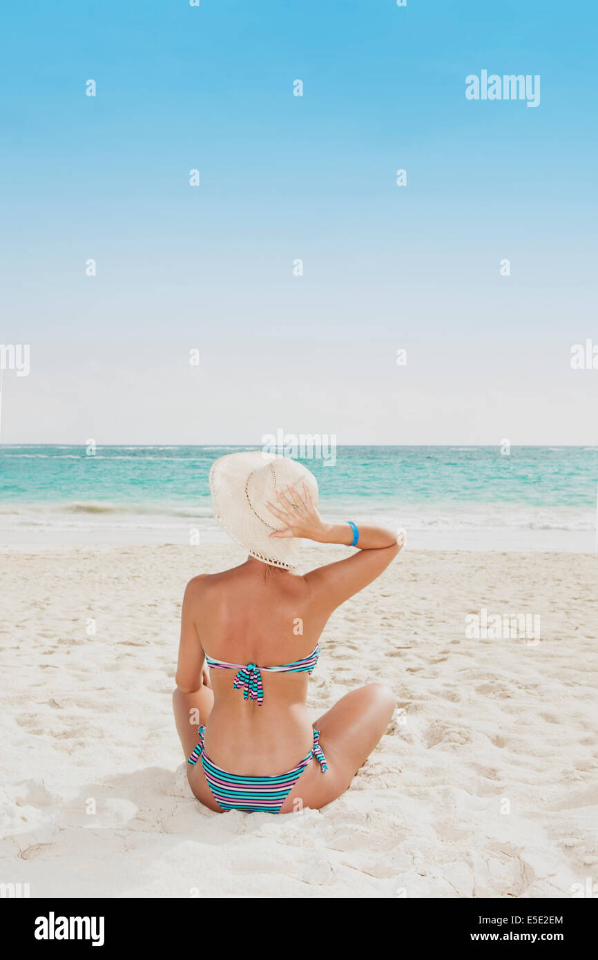 Eine junge Frau sitzt an einem Strand in der Karibik Stockfoto