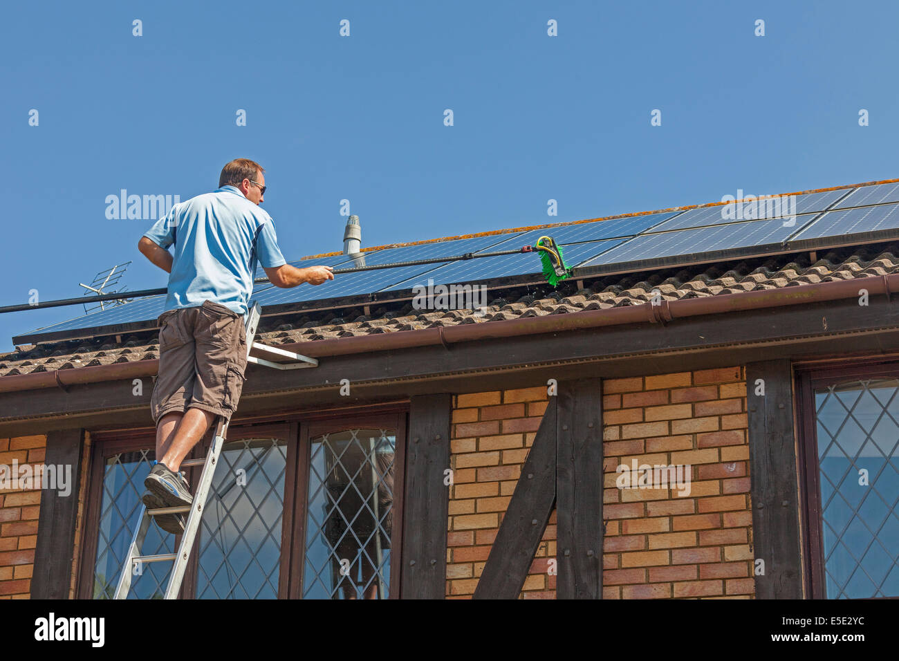 Reinigung angesammelten Schmutz, Dreck und Vogelkot von Sonnenkollektoren auf dem Dach Photovoltaik (PV). JMH6245 Stockfoto