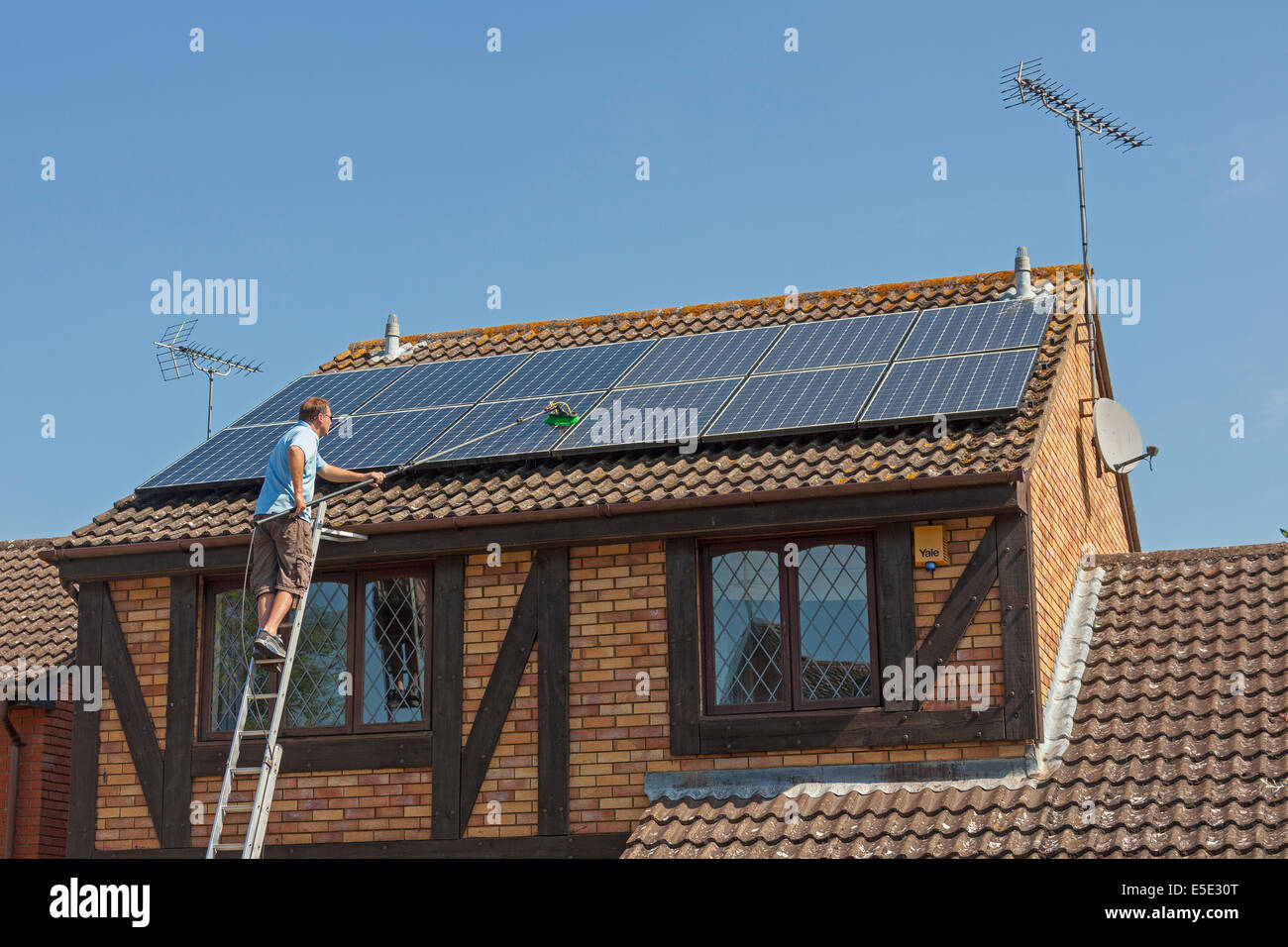Reinigung angesammelten Schmutz, Dreck und Vogelkot von Sonnenkollektoren auf dem Dach Photovoltaik (PV). JMH6247 Stockfoto