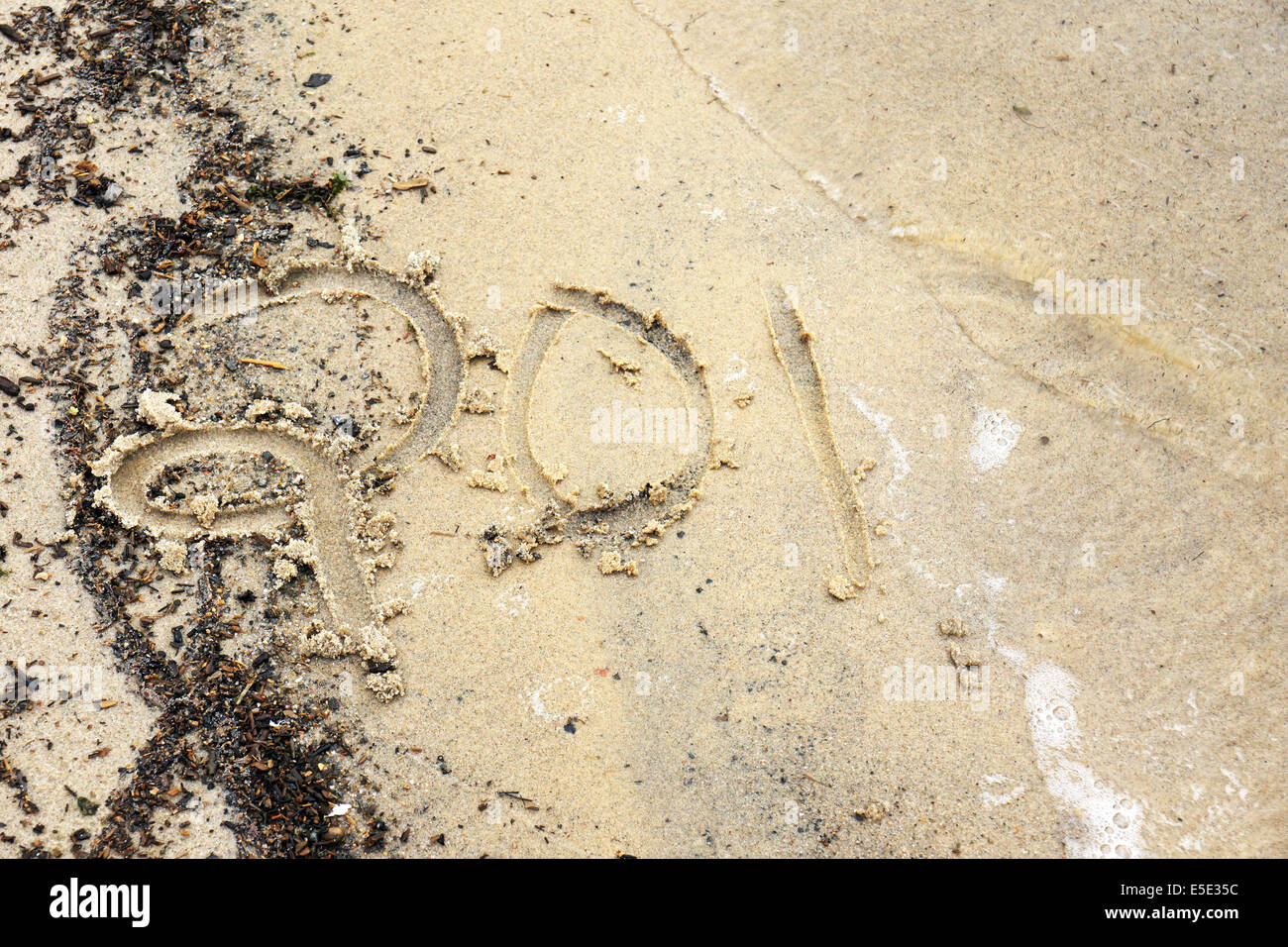 Neujahr-Konzept: Jahr 2014 (oder andere Zahl) geschrieben am Strand von einer Welle weggespült Stockfoto