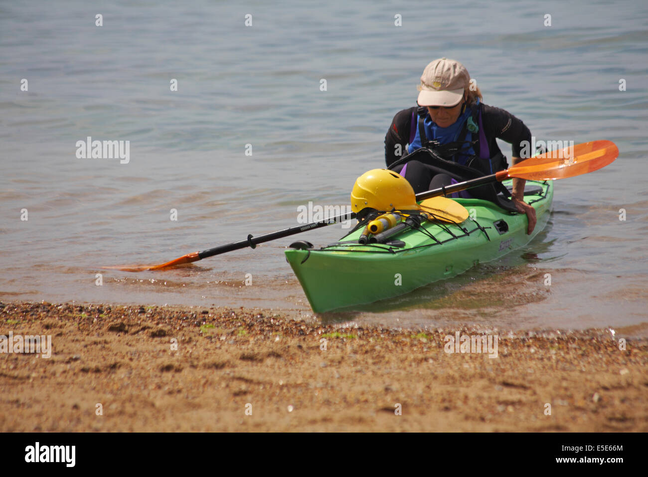 Frau aus Kajak im Meer bei Worbarrow Bay, Isle of Purbeck, Dorset im Juli bekommen Stockfoto