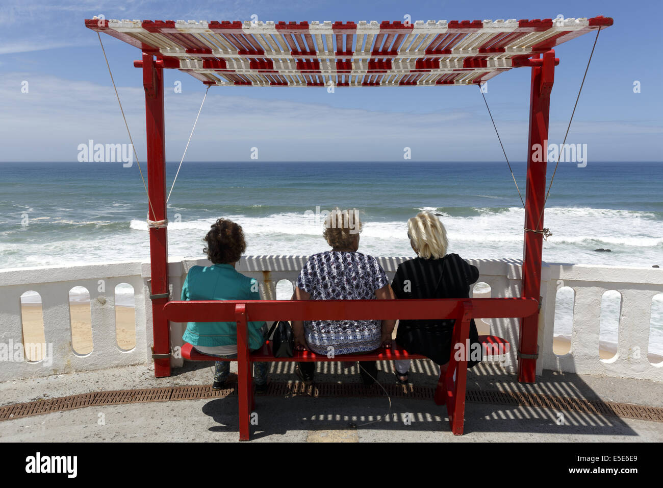 Drei Frauen sitzen auf einer schattigen Bank Blick aus Meer Silverira, Portugal Stockfoto