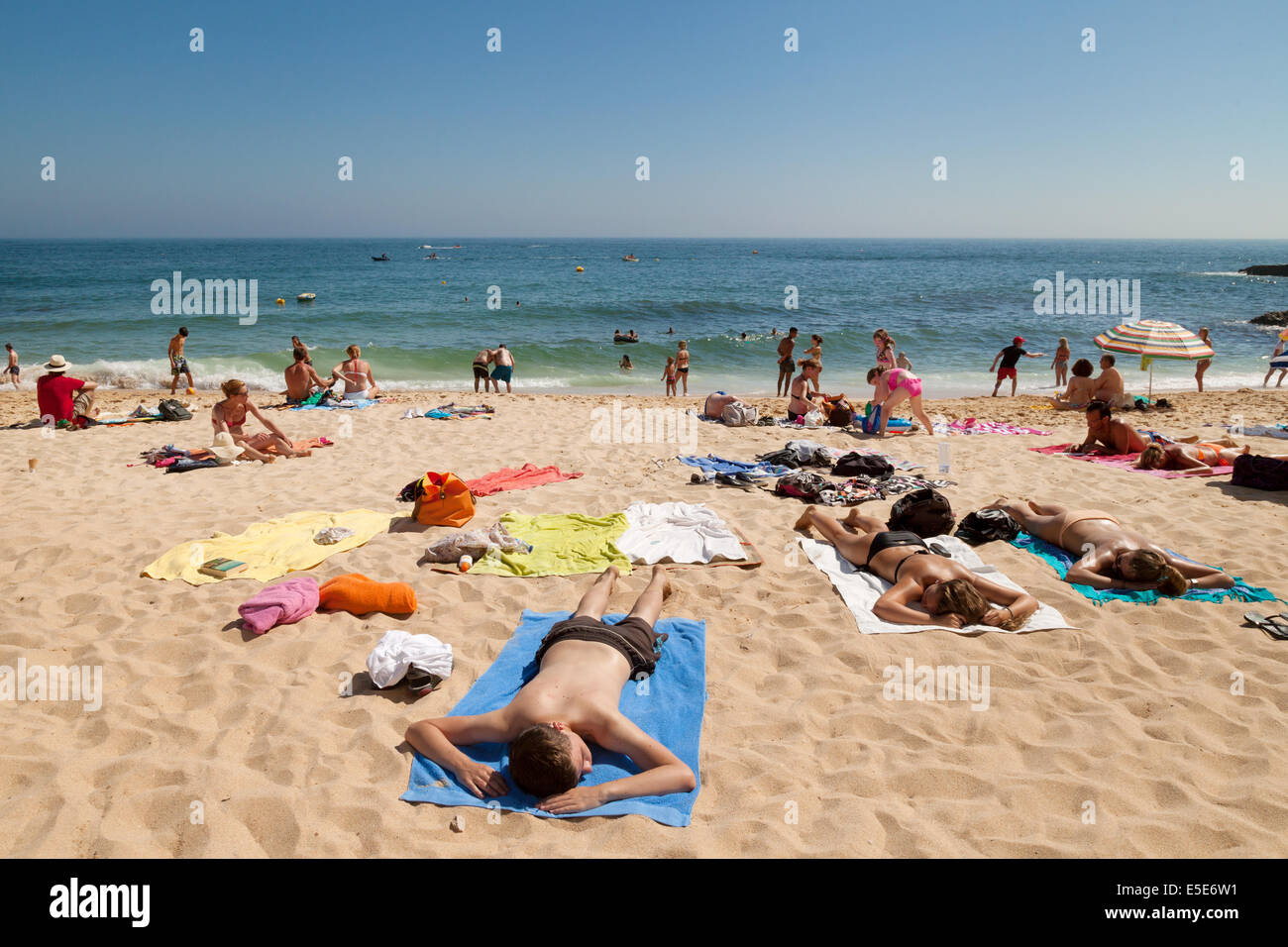 Menschen Sonnenbaden im Sommerurlaub am Strand von Carvoeiro, Algarve, Portugal Europa Stockfoto