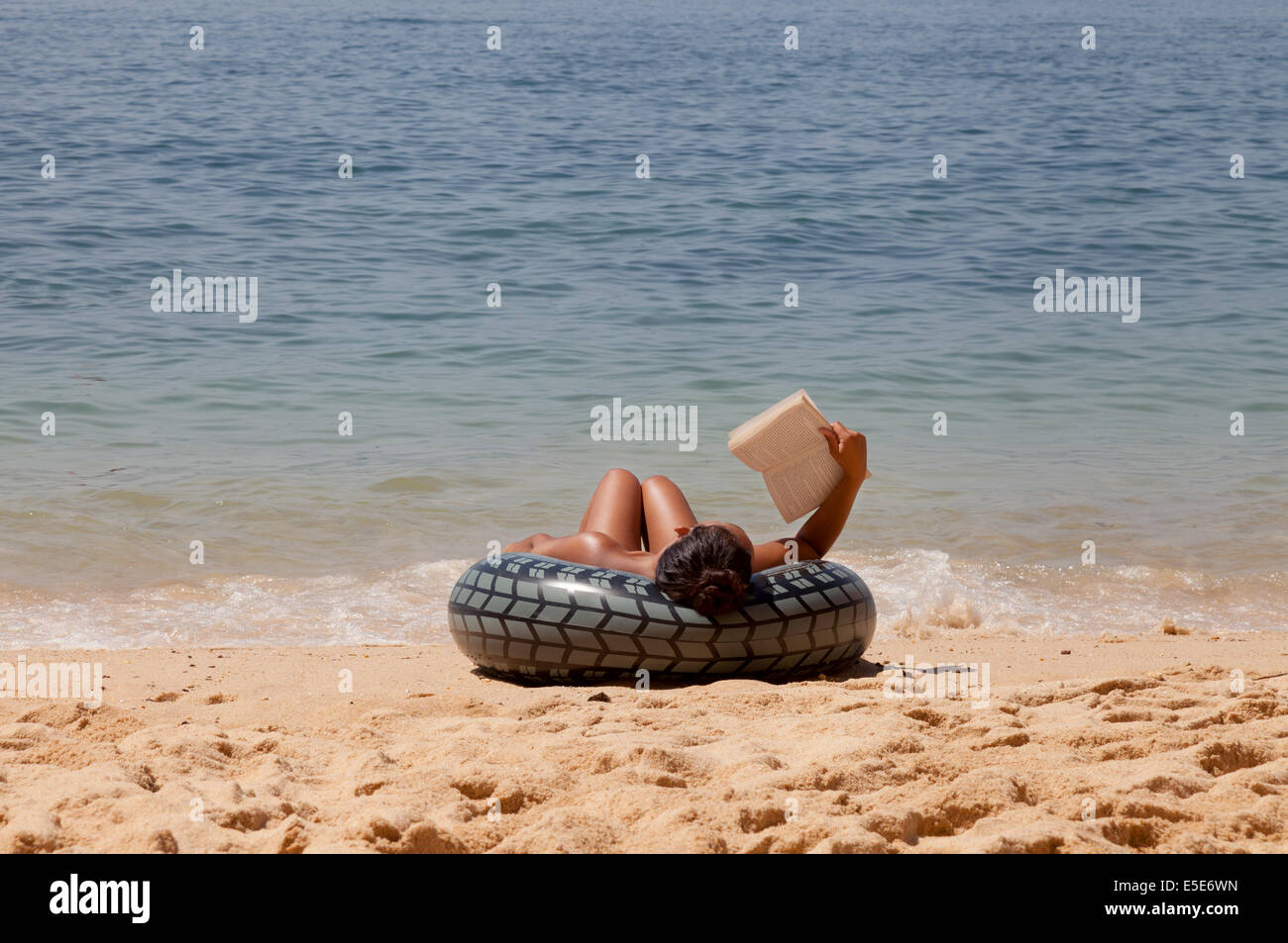 Eine Frau entspannen und lesen ein Buch am Strand im Sommerurlaub, Algarve, Portugal Europa Stockfoto