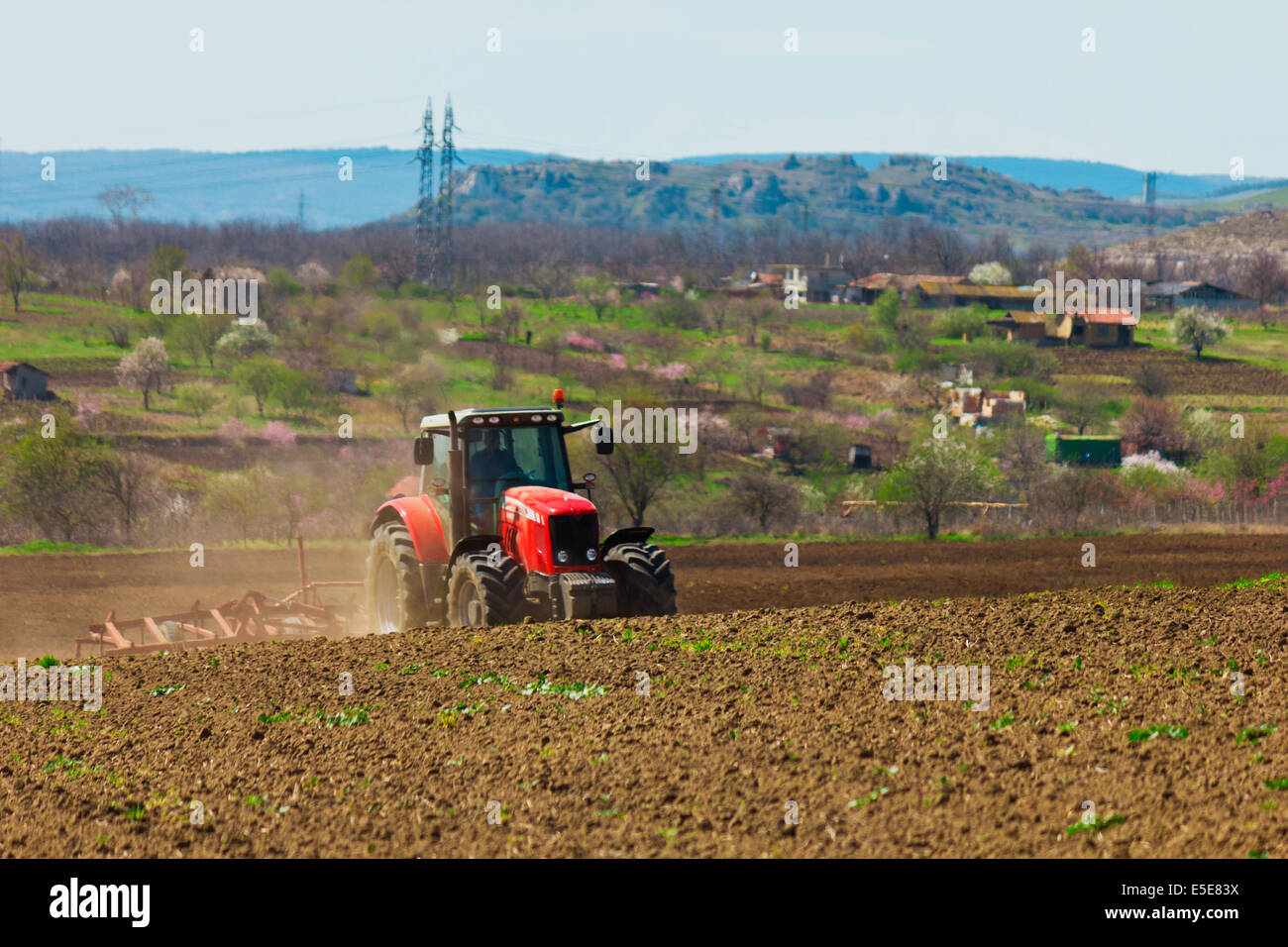 Der Bauer das Feld pflügen. Traktor im Bereich Pflege. Roter Traktor mit einem Pflug in einem Bauernhof-Feld. Traktor und Pflug Stockfoto