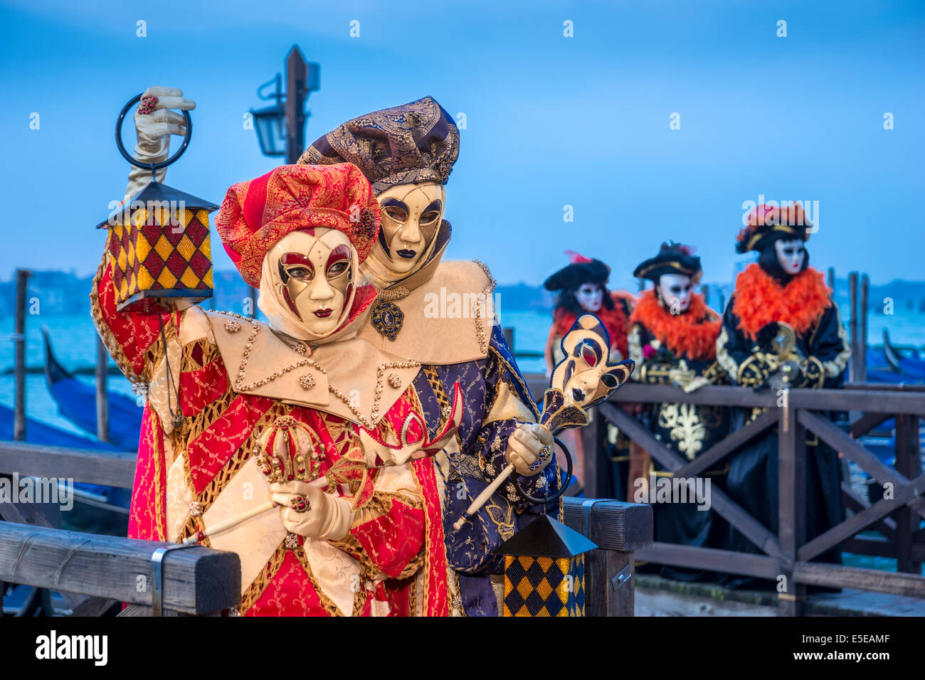 Harlekin kostümierte paar beitreten anderen Karneval Feiernden auf den Gondeln Docks entlang der Uferpromenade von Venedig. Stockfoto